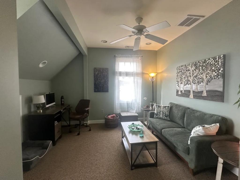 Bright office room with green sofa and ceiling fan